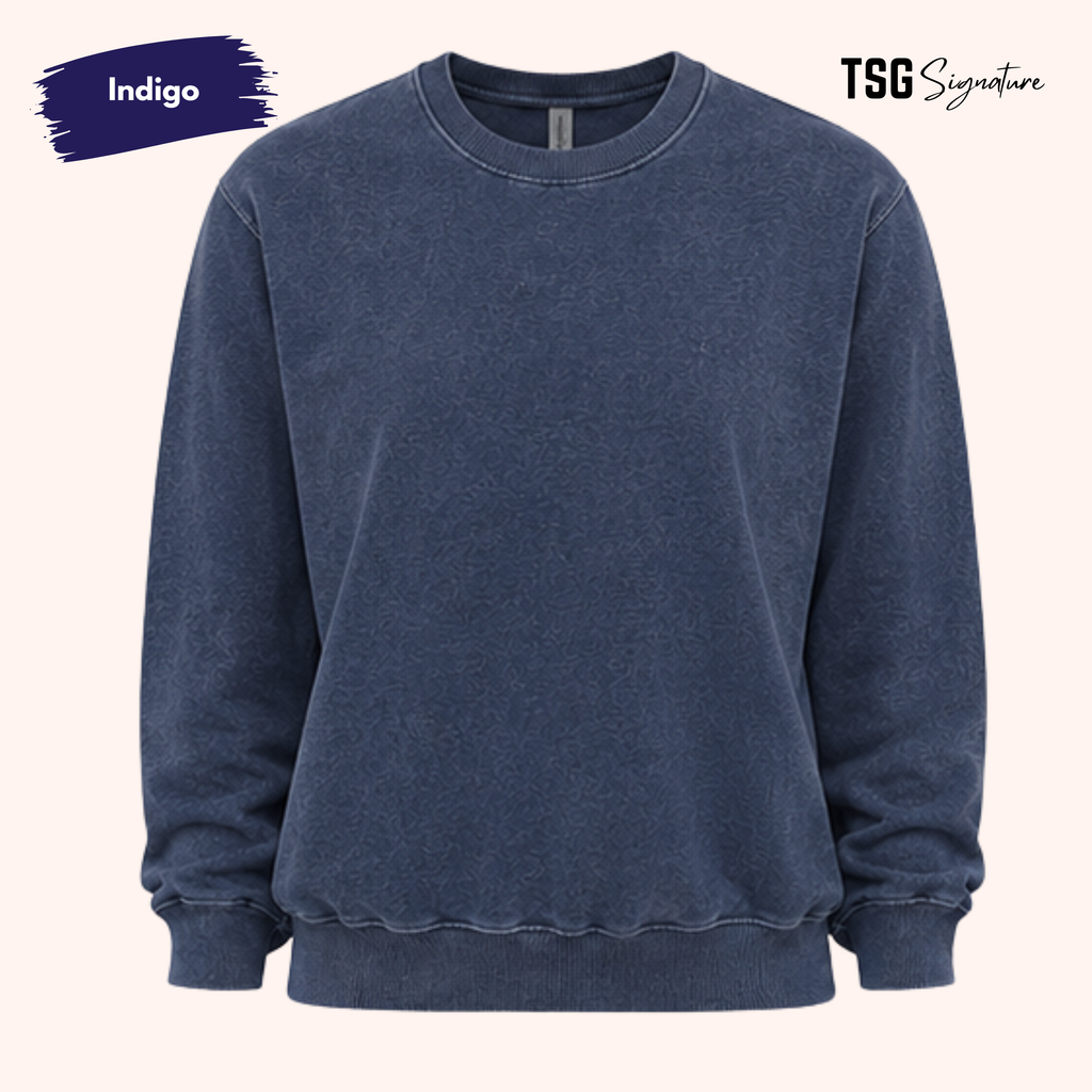 A washed indigo blue crewneck sweatshirt with a raw, distressed finish, shown against a light beige background with 'Indigo' and 'TSG Signature' text overlays.