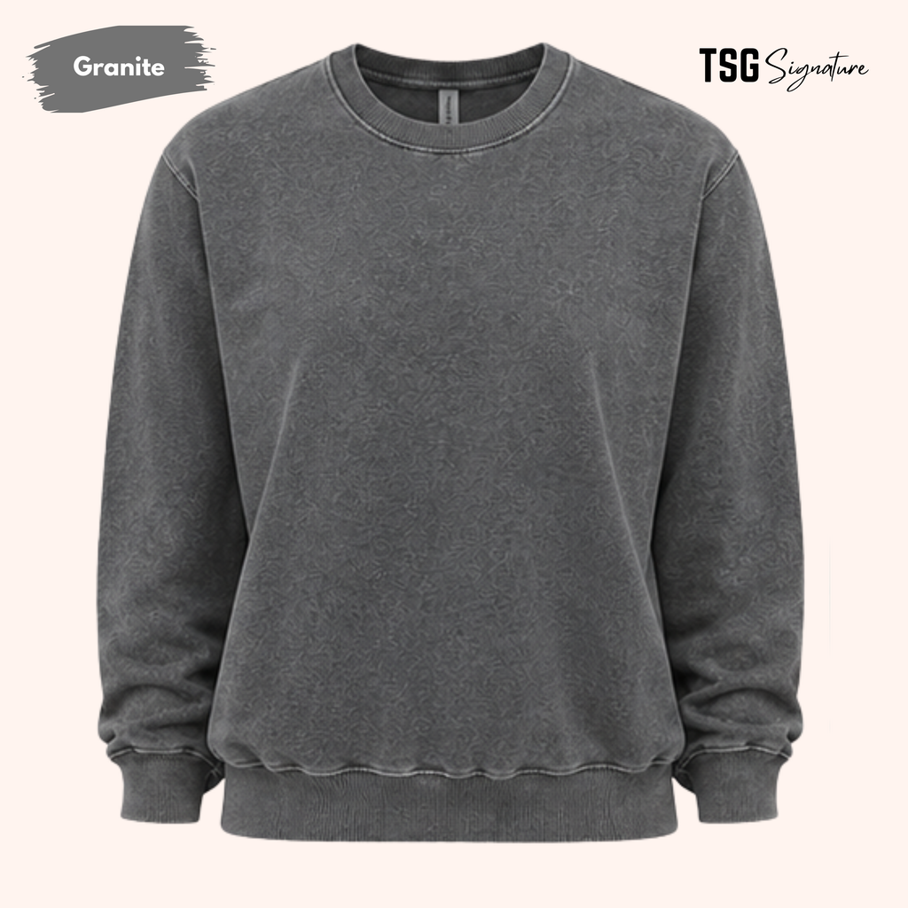 A dark gray mineral-wash crewneck sweatshirt on a light beige background, featuring 'Granite' text in a gray paint brush on the top left and 'TSG Signature' on the top right.