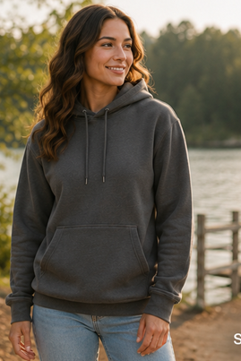 A woman wearing a dark gray hoodie with a front kangaroo pocket and drawstrings, standing outdoors near a lake with trees and a wooden dock in the background. The word 'Smoke' is printed in the bottom right corner.